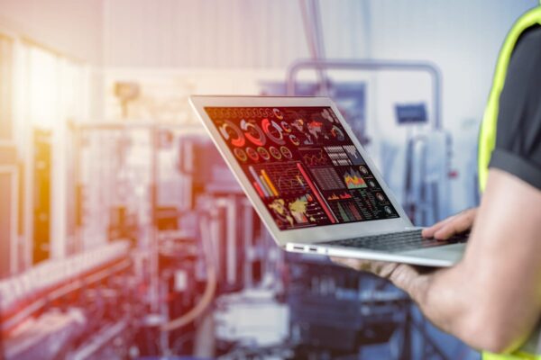 A man holding a laptop planning digital marketing for manufacturing businesses